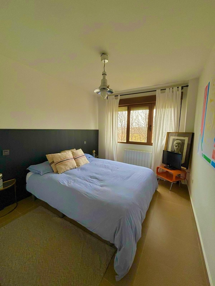 Dormitorio principal con cama doble y cabecero gris