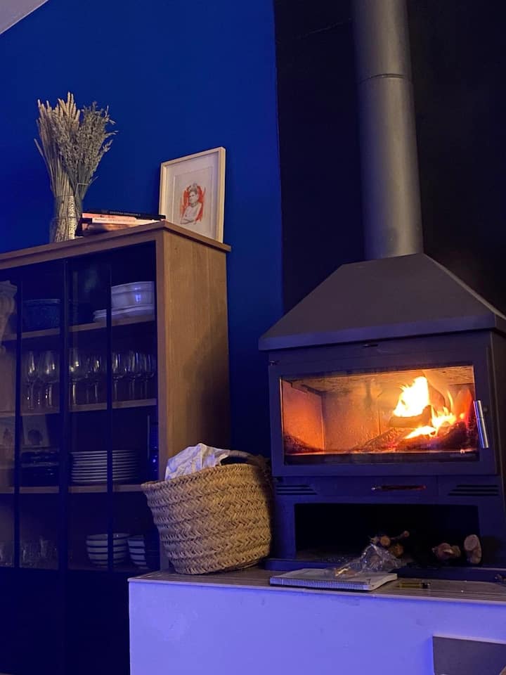 Chimenea de leña encendida en el salón de Casa Rural Teja Vieja